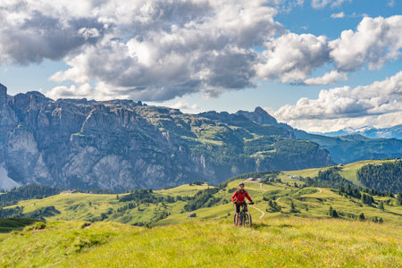 beautiful active senior woman riding her electric mountain bike on the Pralongia Plateau in the Alta Badia Dolomites with awesome Sasso die Santa Cruce summit in Backg, South Tirol and Trentino, Italyの写真素材