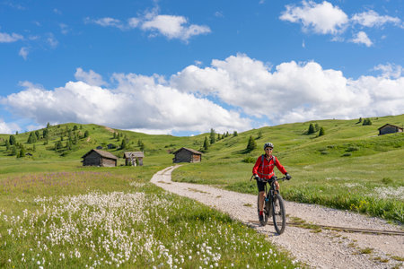 beautiful active senior woman riding her electric mountain bike on the Pralongia Plateau in the Alta Badia Dolomites with awesome Sasso die Santa Cruce summit in Backg, South Tirol and Trentino, Italyの写真素材