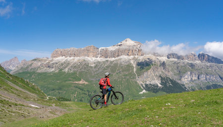 beautiful aczive senior woman riding the famous Sella Ronda mountain bike Trail in Sella mountain group, Dolomites of Selva Wolkenstein, Val Gardena, South Tirol and Trentino, Italyの写真素材
