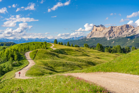 beautiful active senior woman riding her electric mountain bike on the Pralongia Plateau in the Alta Badia Dolomites with awesome Sasso die Santa Cruce summit in Backg, South Tirol and Trentino, Italyの写真素材