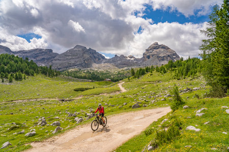 nice active senior woman riding her electric mountain bike in the Fanes high Valley, part of Fanes-Sennes-Braies nature park in the Alta Badia Dolomites, South Tirol and Trentino, Italyの写真素材