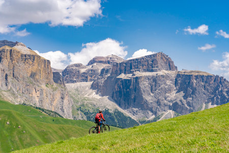 beautiful aczive senior woman riding the famous Sella Ronda mountain bike Trail in Sella mountain group, Dolomites of Selva Wolkenstein, Val Gardena, South Tirol and Trentino, Italyの写真素材