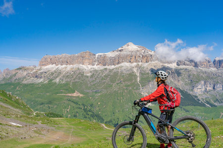 beautiful aczive senior woman riding the famous Sella Ronda mountain bike Trail in Sella mountain group, Dolomites of Selva Wolkenstein, Val Gardena, South Tirol and Trentino, Italyの写真素材