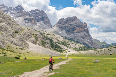 nice active senior woman riding her electric mountain bike in the Fanes high Valley, part of Fanes-Sennes-Braies nature park in the Alta Badia Dolomites, South Tirol and Trentino, Italyの写真素材