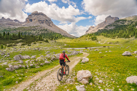 nice active senior woman riding her electric mountain bike in the Fanes high Valley, part of Fanes-Sennes-Braies nature park in the Alta Badia Dolomites, South Tirol and Trentino, Italyの写真素材