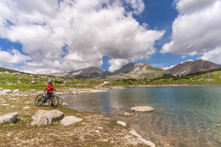 nice active senior woman riding her electric mountain bike in the Fanes high Valley, part of Fanes-Sennes-Braies nature park in the Alta Badia Dolomites, South Tirol and Trentino, Italyの写真素材