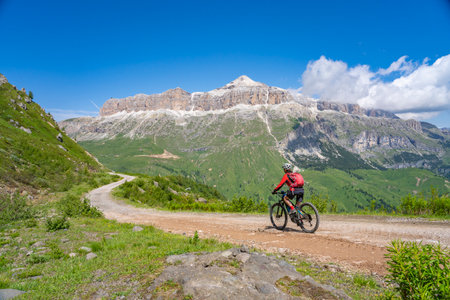 beautiful aczive senior woman riding the famous Sella Ronda mountain bike Trail in Sella mountain group, Dolomites of Selva Wolkenstein, Val Gardena, South Tirol and Trentino, Italyの写真素材