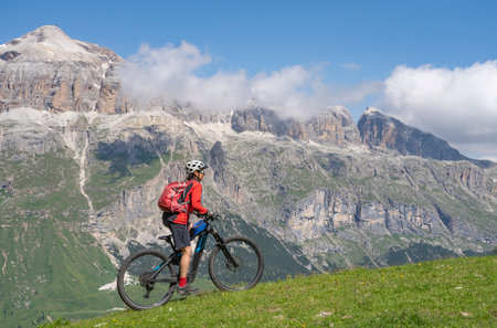 beautiful aczive senior woman riding the famous Sella Ronda mountain bike Trail in Sella mountain group, Dolomites of Selva Wolkenstein, Val Gardena, South Tirol and Trentino, Italyの写真素材