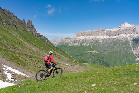 beautiful aczive senior woman riding the famous Sella Ronda mountain bike Trail in Sella mountain group, Dolomites of Selva Wolkenstein, Val Gardena, South Tirol and Trentino, Italyの写真素材