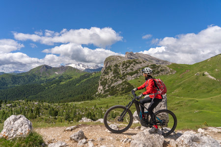 nice active senior woman riding her electric mountain bike up to Valparola Pass in the Alta Badia Dolomites, South Tirol and Trentino, Italyの写真素材