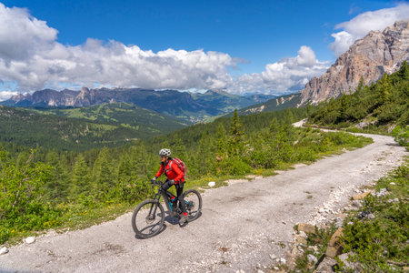 nice active senior woman riding her electric mountain bike up to Valparola Pass in the Alta Badia Dolomites, South Tirol and Trentino, Italyの写真素材