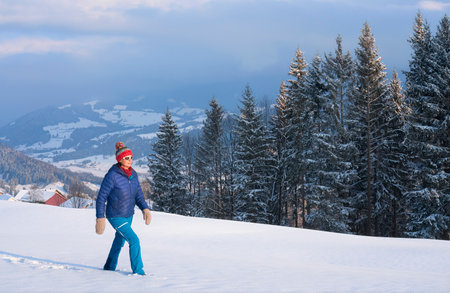Man in blue jacket and red cap on the background of winter mountainsの写真素材