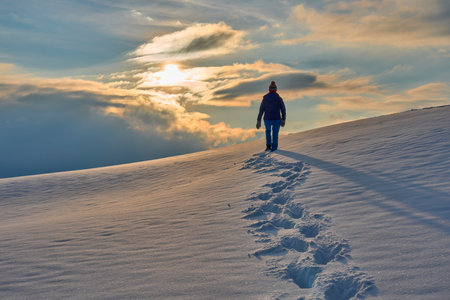 Hiker walking on snow in winter mountains at sunset. Beautiful winter landscape.の写真素材