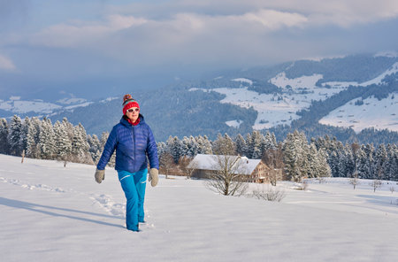 A young woman walks in the snow in the mountains. Winter holidays.の写真素材