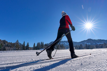 beautiful active senior woman cross-country skiing in fresh fallen powder snow in the Allgau alps near Balderschwang, Bavaria, Germanyの写真素材