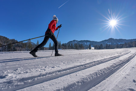 beautiful active senior woman cross-country skiing in fresh fallen powder snow in the Allgau alps near Balderschwang, Bavaria, Germanyの写真素材