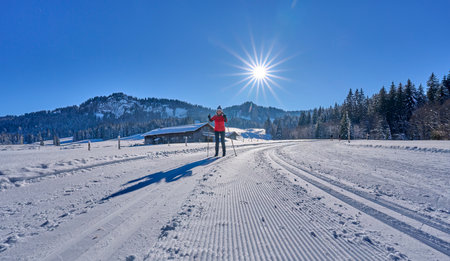 beautiful active senior woman cross-country skiing in fresh fallen powder snow in the Allgau alps near Balderschwang, Bavaria, Germanyの写真素材