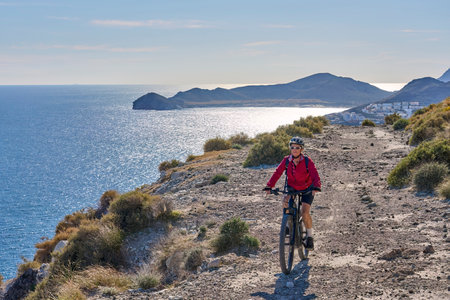 Cyclist Riding the Mountain Bike on the Trail on the Beautiful Island of Santoriniの写真素材