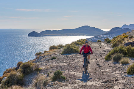 nice senior man cycling with her electric mountain bike in the volcanic nature park of Cabo de Gata, Costa del Sol, Andaluciaの写真素材