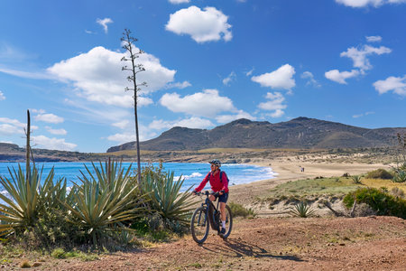 nice senior man cycling with her electric mountain bike in the volcanic nature park of Cabo de Gata, Costa del Sol, Andaluciaの写真素材