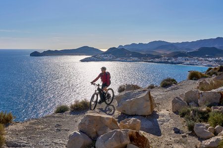 nice senior man cycling with her electric mountain bike in the volcanic nature park of Cabo de Gata, Costa del Sol, Andaluciaの写真素材