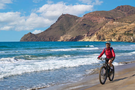 nice senior man cycling with her electric mountain bike in the volcanic nature park of Cabo de Gata, Costa del Sol, Andaluciaの写真素材