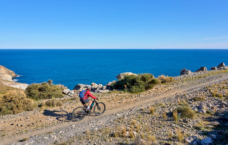 nice senior man cycling with her electric mountain bike in the volcanic nature park of Cabo de Gata, Costa del Sol, Andaluciaの写真素材