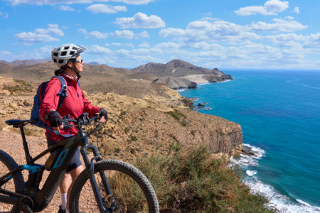 nice senior man cycling with her electric mountain bike in the volcanic nature park of Cabo de Gata, Costa del Sol, Andaluciaの写真素材