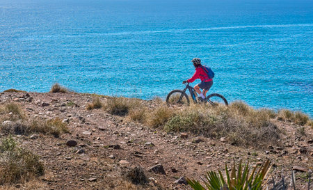 nice senior man cycling with her electric mountain bike in the volcanic nature park of Cabo de Gata, Costa del Sol, Andaluciaの写真素材