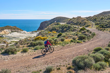nice senior man cycling with her electric mountain bike in the volcanic nature park of Cabo de Gata, Costa del Sol, Andaluciaの写真素材