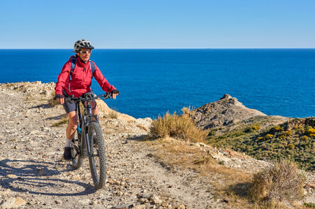 nice senior man cycling with her electric mountain bike in the volcanic nature park of Cabo de Gata, Costa del Sol, Andaluciaの写真素材