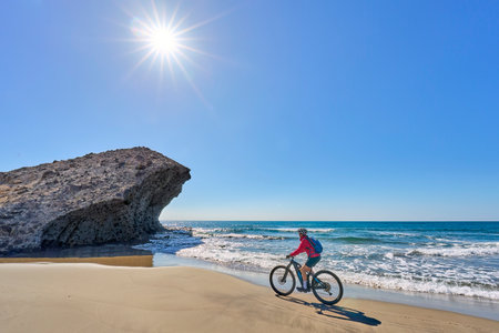 nice senior man cycling with her electric mountain bike in the volcanic nature park of Cabo de Gata, Costa del Sol, Andaluciaの写真素材