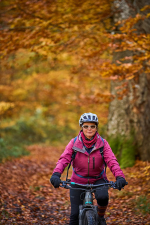 Mountain biking in the autumn forest. Woman riding a bike on a trail in the forest.の写真素材
