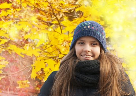 Portrait of smiling young girl in cold weather dressed warm hat in autumnの写真素材