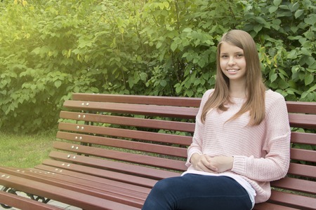 Beautiful teenager girl  sitting on the benchの写真素材
