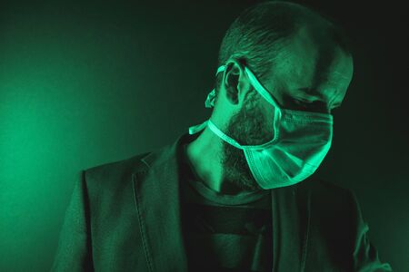 Looking to the right of A young Caucasian man with a scarf in the coronavirus pandemic with a green background, Covid-19の写真素材