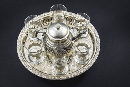 Top view of a metallic mug and Turkish crystal glasses on a metallic circular flag with black backgroundの写真素材
