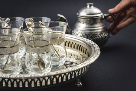 Detail of a metallic cup and Turkish glasses, a nice tableware of Arab origin with a black backgroundの写真素材