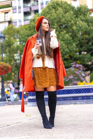 Street style, caucasian dressed in red and with skirt sitting in the city having a coffeeの写真素材