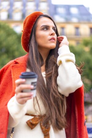 Street style, portrait of a caucasian brunette dressed in red in the city having a coffeeの写真素材