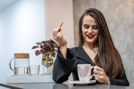 A young smiling Caucasian brunette in a cafe having coffee, street styleの写真素材