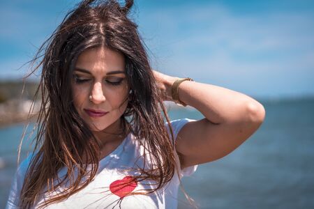 Lifestyle, a dreamy brunette in a white t-shirt, a red short skirt by the seaの写真素材