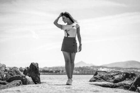 Street style, young brunette in white t-shirt walking along the promenade, black and white photoの写真素材