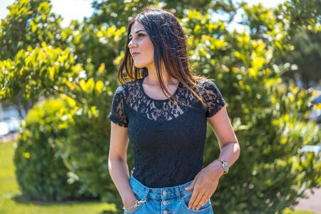 Street style, young brunette in a black t-shirt and jeans shorts looking to the leftの写真素材
