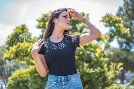 Lifestyle, a pretty young brunette in a black T-shirt and ripped denim shorts covering her face with her handの写真素材