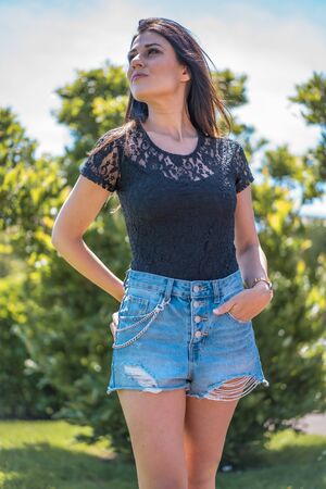 Lifestyle, portrait of a young pretty brunette in a black t-shirt and ripped denim shortsの写真素材