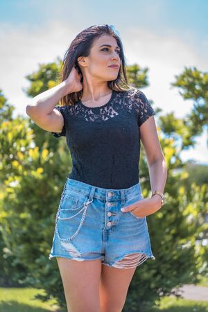 Lifestyle, portrait of a serious young brunette in a black t-shirt and shorts looking to the right and looking at the horizonの写真素材