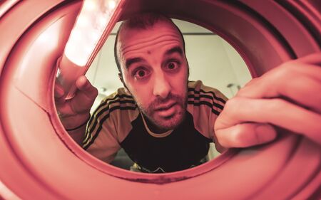 Am I escaping from quarantine through this hole? Photo inside a washing machine with a red lightの写真素材