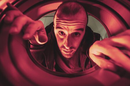 I'm leaving this world, A young man trying to get into a hole with a red lightの写真素材