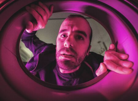 Interior of a washing machine photo of a young Caucasian man, with dark blue and red lightsの写真素材